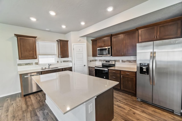 kitchen featuring appliances with stainless steel finishes, dark hardwood / wood-style flooring, a kitchen island, and sink