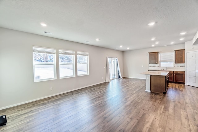 kitchen featuring sink, wood-type flooring, a textured ceiling, and a kitchen island