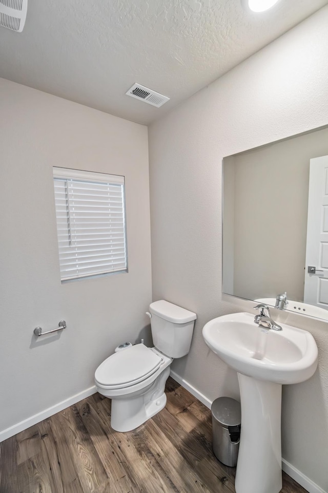 bathroom with toilet, a textured ceiling, and hardwood / wood-style floors