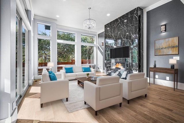 living room featuring crown molding, a fireplace, an inviting chandelier, and light hardwood / wood-style floors