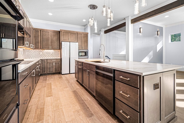 kitchen featuring tasteful backsplash, decorative light fixtures, sink, a kitchen island with sink, and appliances with stainless steel finishes