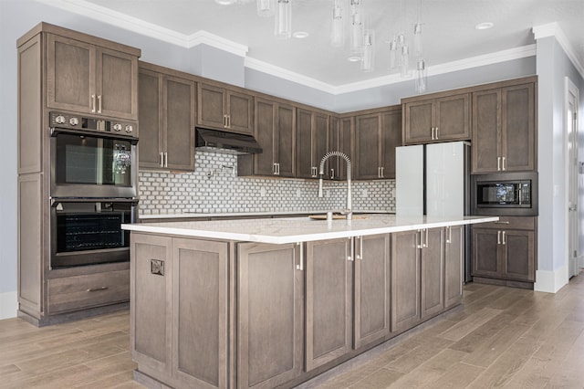 kitchen featuring backsplash, light hardwood / wood-style flooring, a kitchen island with sink, appliances with stainless steel finishes, and ornamental molding