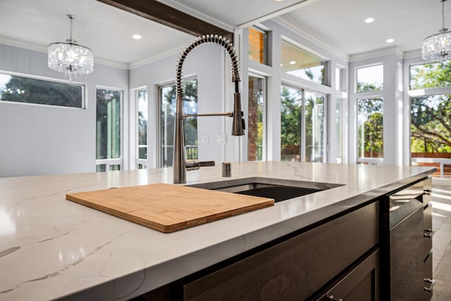 kitchen featuring decorative light fixtures, sink, crown molding, and a notable chandelier