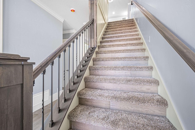 staircase featuring crown molding and hardwood / wood-style flooring