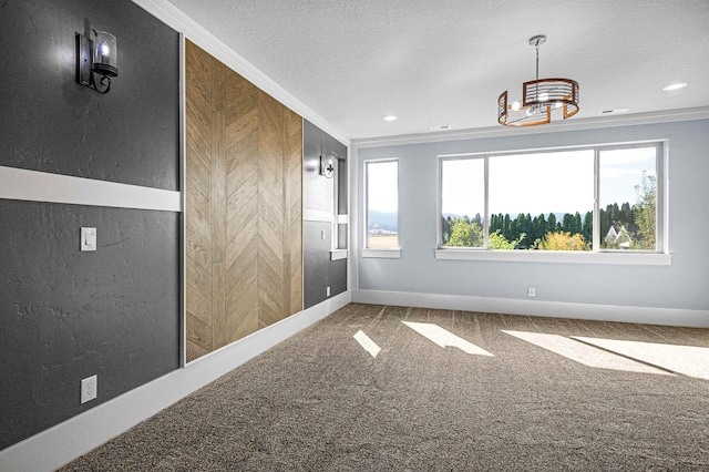 carpeted empty room with ornamental molding and a textured ceiling