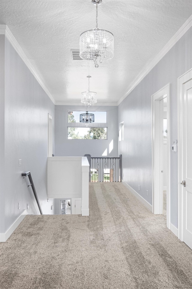 hallway with a textured ceiling, ornamental molding, carpet flooring, and a chandelier