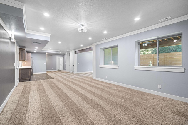 unfurnished living room featuring a textured ceiling, crown molding, and carpet