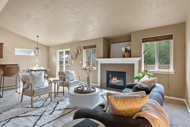 carpeted living room featuring a textured ceiling, a tiled fireplace, and vaulted ceiling