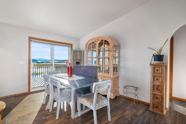 dining area with a water view and dark wood-type flooring