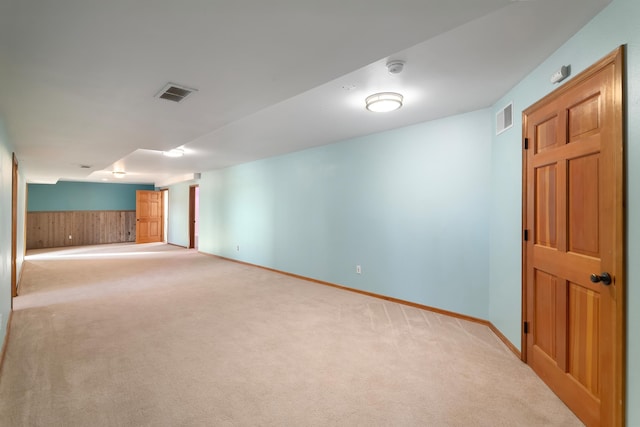 unfurnished room with light carpet and wooden walls