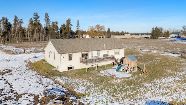 snow covered rear of property with a playground and a deck