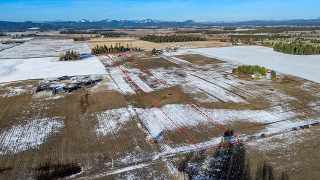 snowy aerial view featuring a rural view and a mountain view