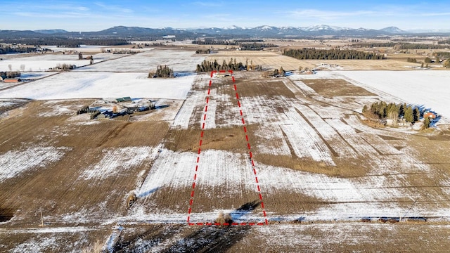 snowy aerial view with a rural view and a mountain view