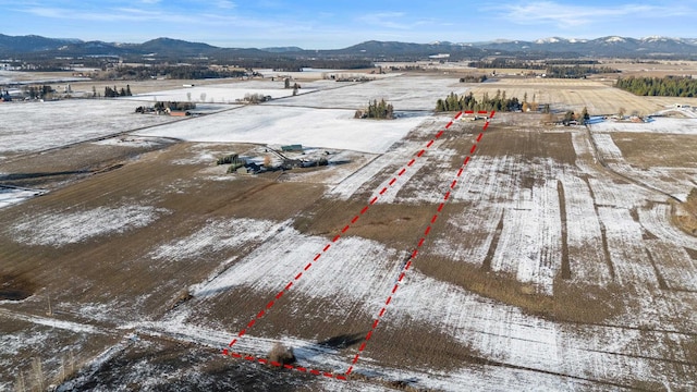 snowy aerial view featuring a mountain view and a rural view