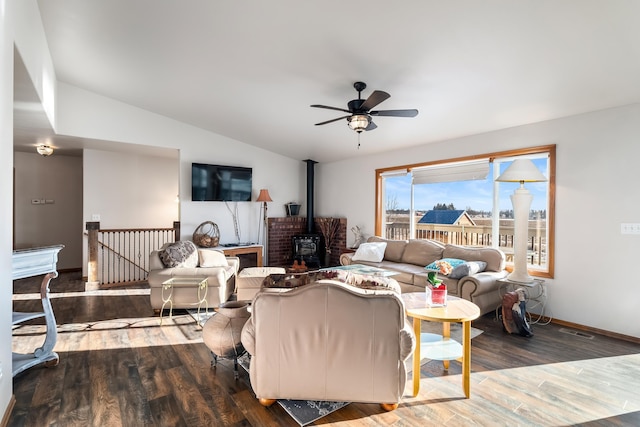 living room featuring ceiling fan, a wood stove, hardwood / wood-style floors, and vaulted ceiling