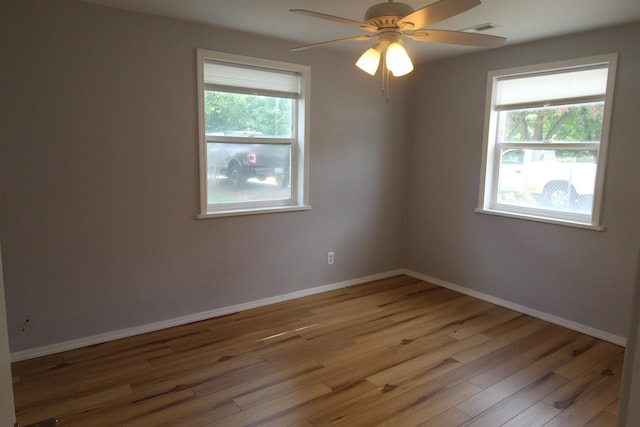 unfurnished room featuring ceiling fan, a healthy amount of sunlight, and hardwood / wood-style floors