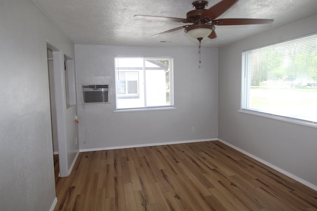 unfurnished room featuring wood-type flooring, a healthy amount of sunlight, a wall unit AC, and ceiling fan