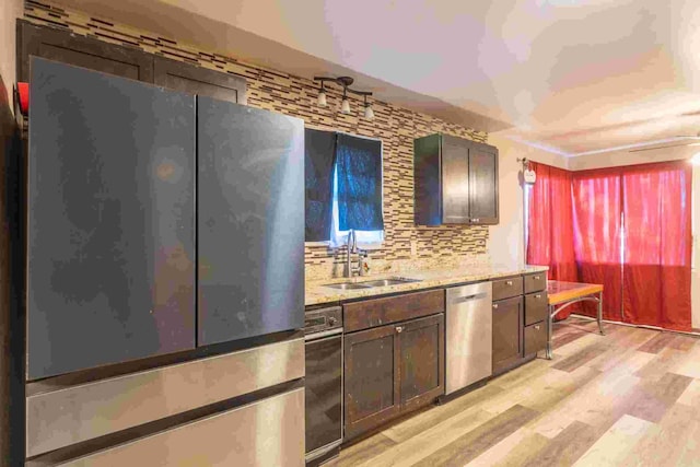 kitchen with tasteful backsplash, sink, stainless steel dishwasher, dark brown cabinetry, and light hardwood / wood-style flooring