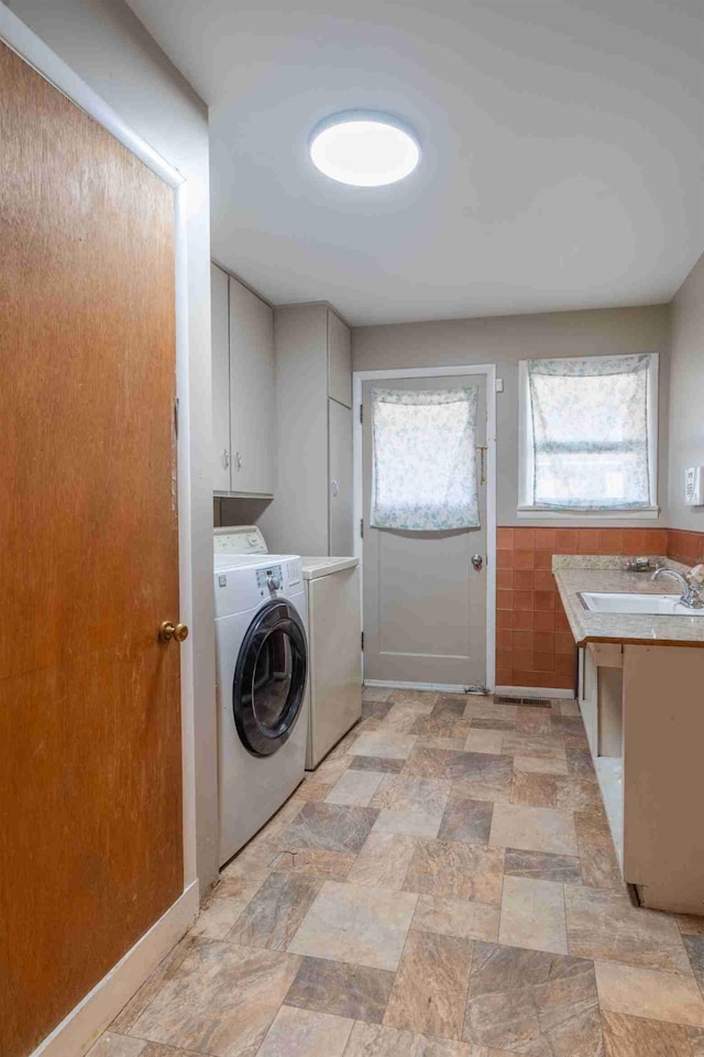 laundry room with cabinets, sink, tile walls, and washer and clothes dryer