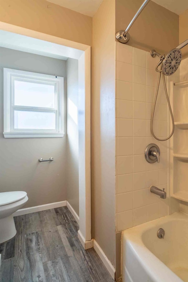 bathroom with wood-type flooring, toilet, and tiled shower / bath