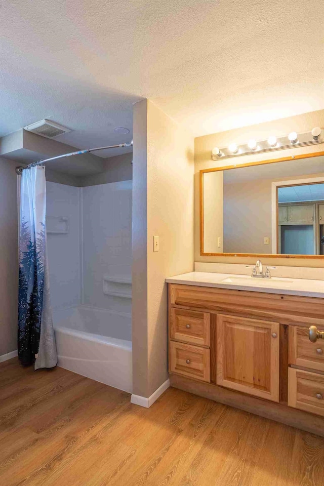 bathroom with wood-type flooring, shower / bath combo, and a textured ceiling