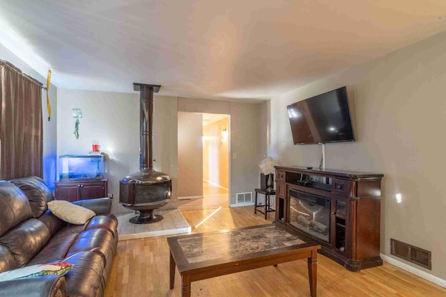 living room with a wood stove and light hardwood / wood-style floors