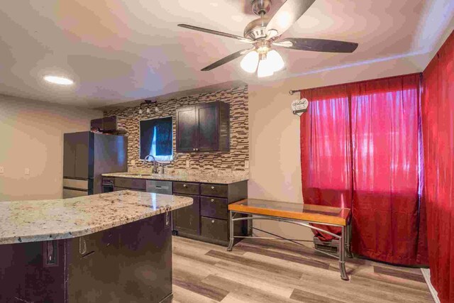 kitchen with sink, light wood-type flooring, stainless steel refrigerator, ceiling fan, and decorative backsplash