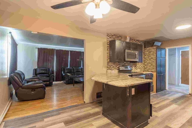 kitchen featuring backsplash, stainless steel appliances, kitchen peninsula, and light wood-type flooring