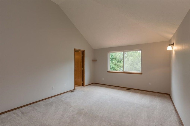 carpeted empty room featuring vaulted ceiling