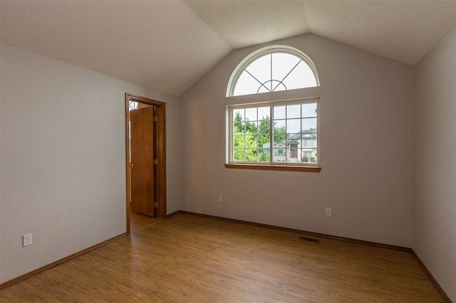 unfurnished room with lofted ceiling and light hardwood / wood-style flooring