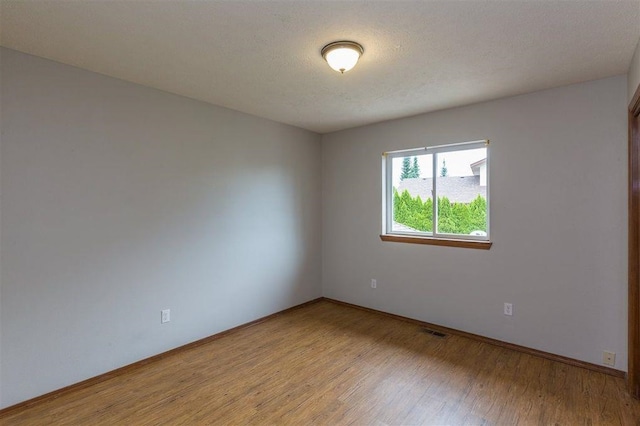 empty room featuring a textured ceiling and wood-type flooring