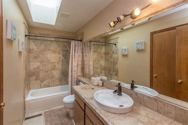 full bathroom with tile patterned floors, vanity, a skylight, shower / bath combination with curtain, and toilet