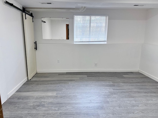 basement with a barn door and hardwood / wood-style flooring