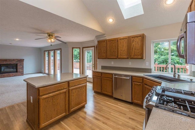 kitchen featuring ceiling fan, appliances with stainless steel finishes, a fireplace, a textured ceiling, and sink