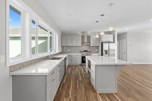kitchen featuring a sink, stainless steel appliances, tasteful backsplash, and wall chimney exhaust hood