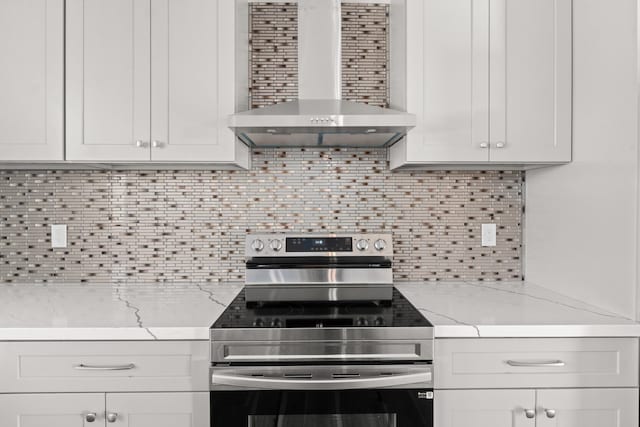 kitchen with stainless steel electric range oven, light stone countertops, backsplash, and wall chimney exhaust hood