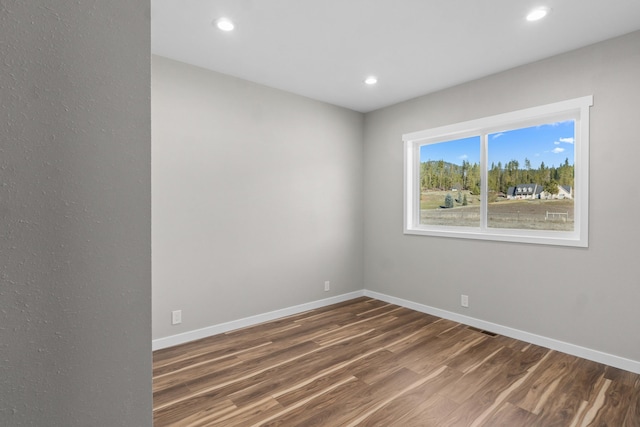 empty room with visible vents, recessed lighting, baseboards, and wood finished floors