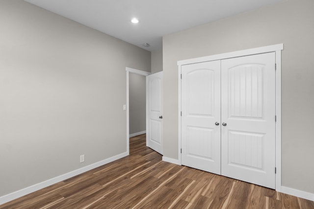 unfurnished bedroom featuring a closet, recessed lighting, dark wood-type flooring, and baseboards