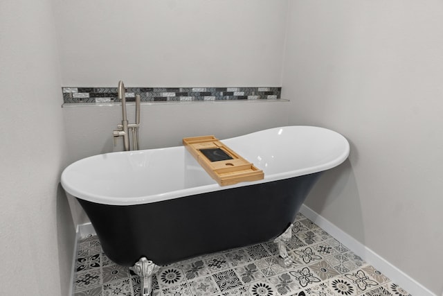 bathroom with baseboards, a freestanding bath, and tile patterned flooring