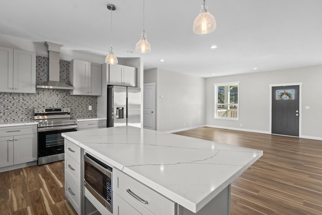 kitchen with backsplash, a kitchen island, appliances with stainless steel finishes, wall chimney exhaust hood, and dark wood-style flooring