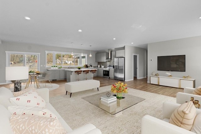 living room featuring recessed lighting, baseboards, and light wood finished floors