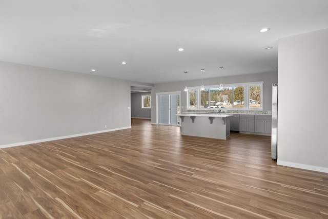 unfurnished living room featuring recessed lighting, a chandelier, baseboards, and dark wood-style floors
