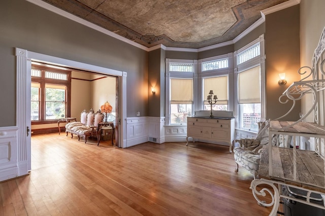 sitting room with ornamental molding, a wealth of natural light, and light wood-type flooring