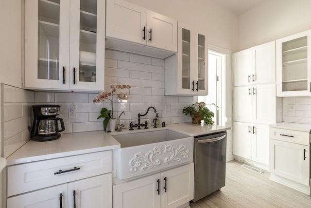 kitchen with sink, white cabinetry, tasteful backsplash, light hardwood / wood-style flooring, and stainless steel dishwasher