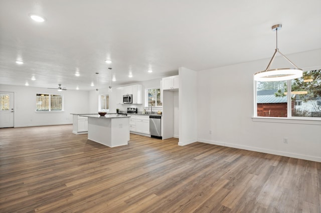 kitchen featuring stainless steel appliances, white cabinetry, hanging light fixtures, and a kitchen island