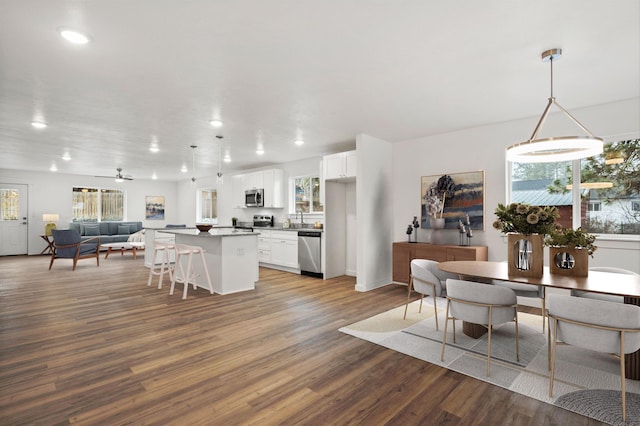 dining space with ceiling fan, sink, and wood-type flooring