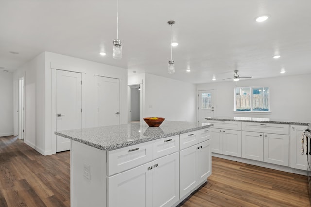 kitchen with white cabinetry, ceiling fan, dark hardwood / wood-style flooring, hanging light fixtures, and a center island