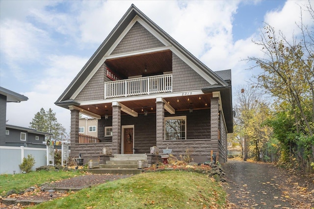 craftsman inspired home with a front yard, covered porch, and a balcony