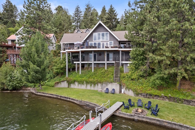 back of house featuring a water view, a yard, a balcony, and a fire pit