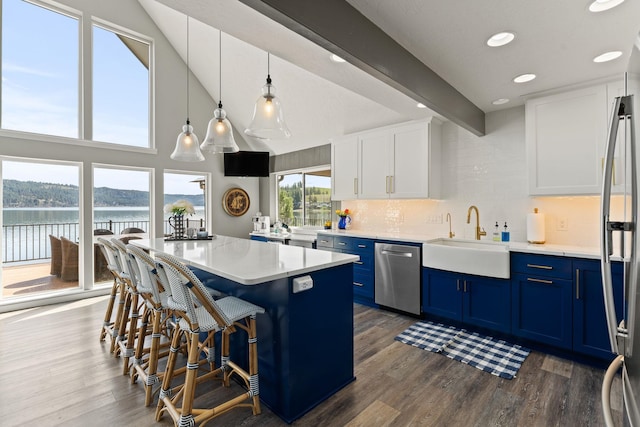 kitchen with appliances with stainless steel finishes, blue cabinets, white cabinets, and hanging light fixtures